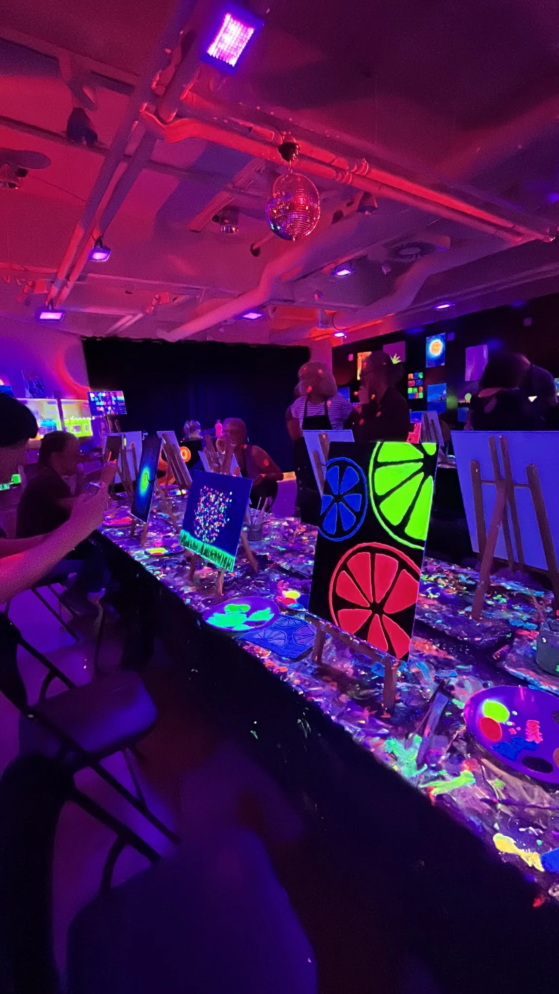 Rembrandt van Wine blacklight studio with participants and neon artwork