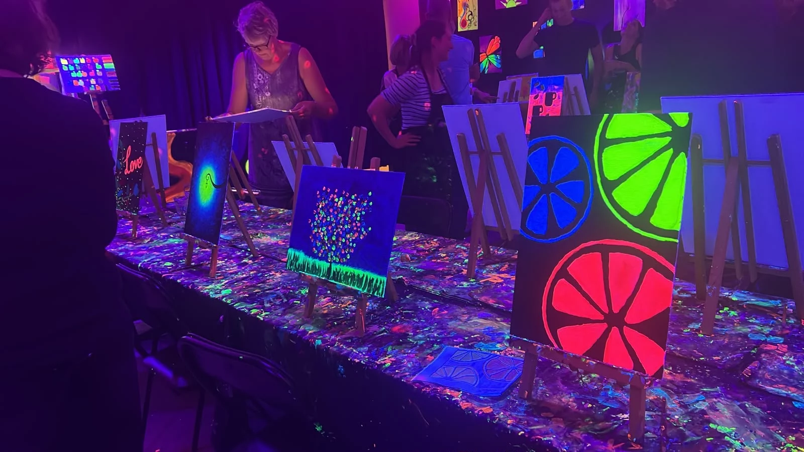 Painting table with easels and neon artwork during Rembrandt van Wine in Amsterdam